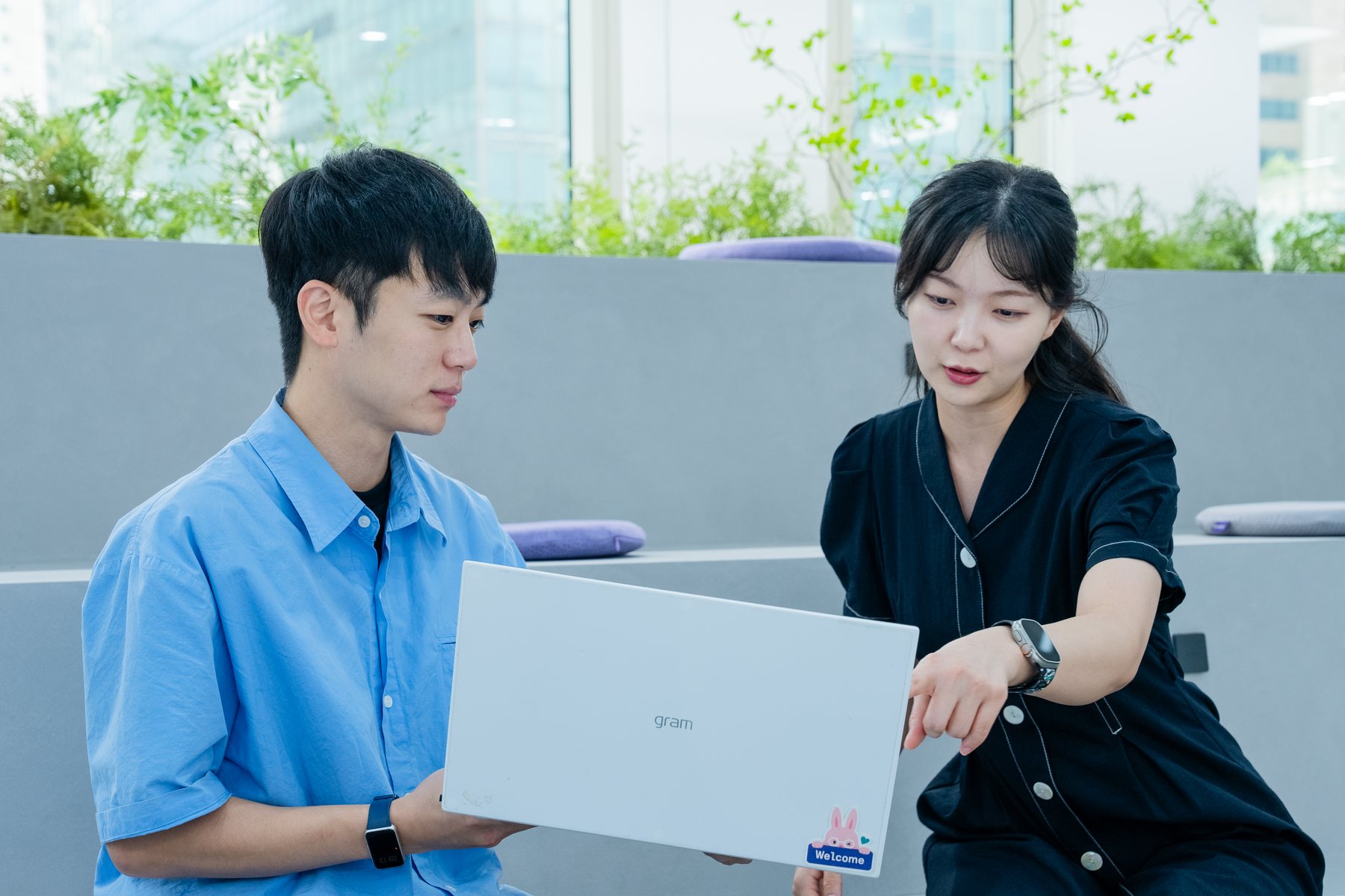 라운지에서 노트북 화면을 함께 보며 의견을 나누는 두 동료